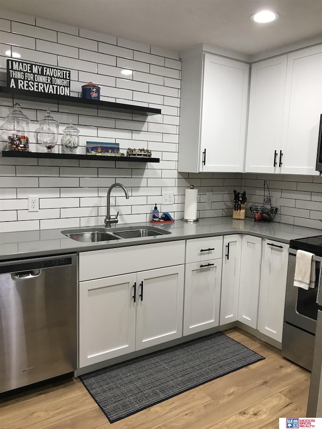 kitchen featuring decorative backsplash, sink, white cabinets, light wood-type flooring, and stainless steel appliances