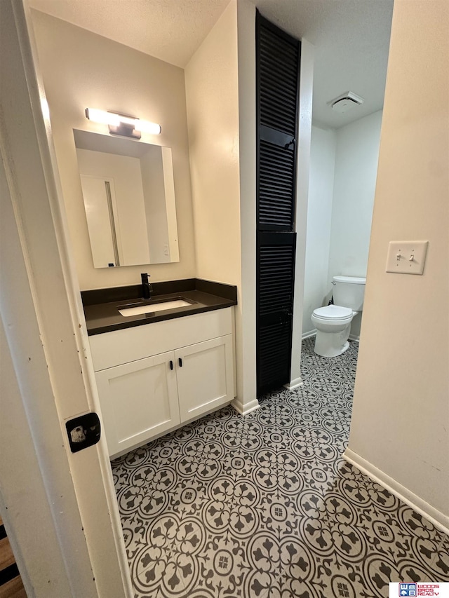 bathroom with a textured ceiling, toilet, and vanity