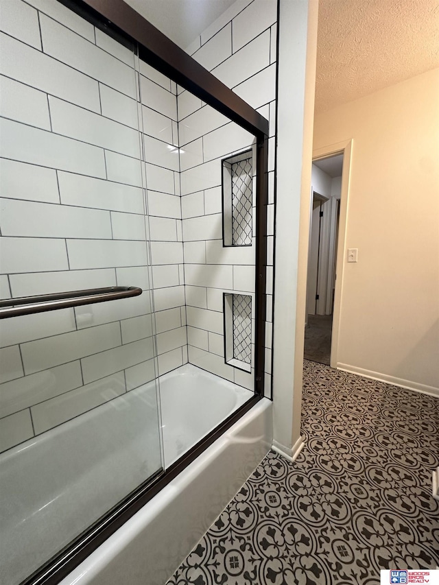 bathroom featuring bath / shower combo with glass door and a textured ceiling