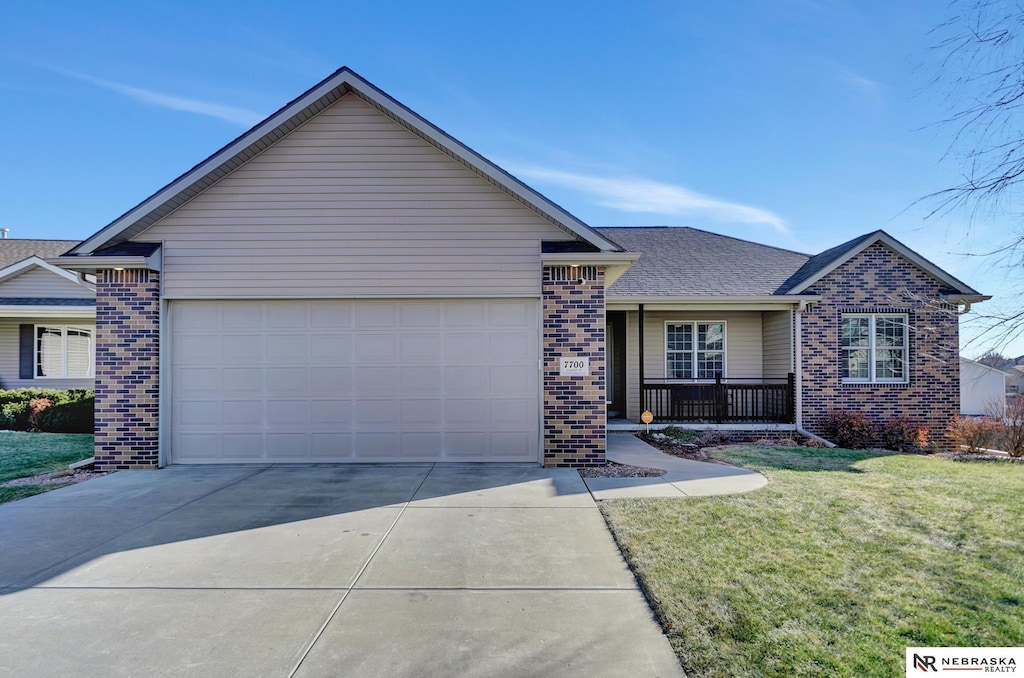 ranch-style home featuring covered porch, a front yard, and a garage