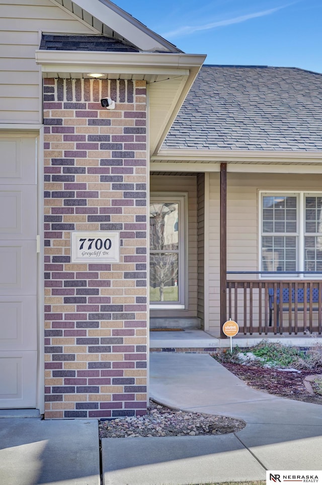 view of exterior entry featuring a garage and a porch