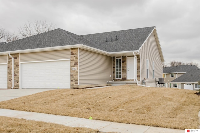 ranch-style home featuring central air condition unit, a garage, and a front lawn