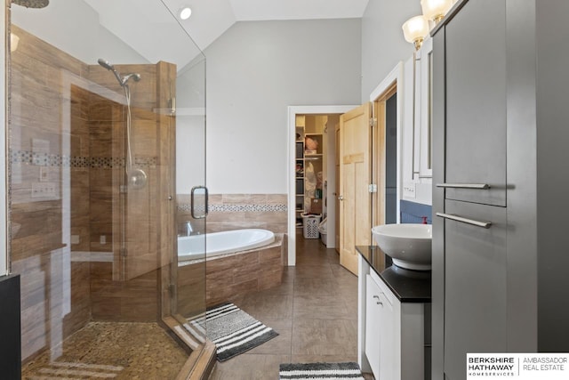 bathroom featuring tile patterned floors, vanity, separate shower and tub, and vaulted ceiling