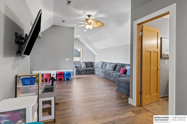 living room with light hardwood / wood-style floors, ceiling fan, and vaulted ceiling