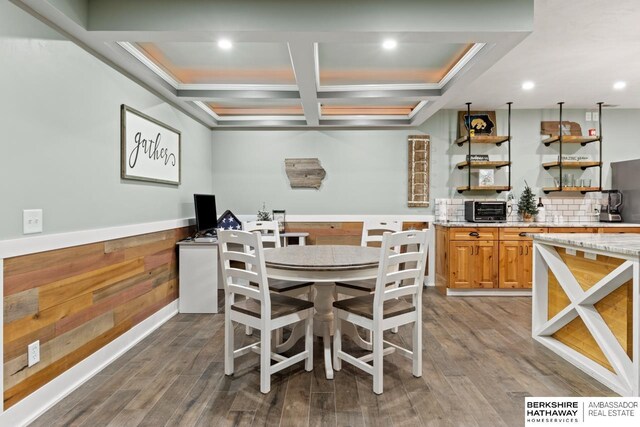 dining area featuring hardwood / wood-style flooring, coffered ceiling, wooden walls, and crown molding