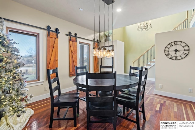 dining space with hardwood / wood-style floors, a notable chandelier, and a barn door