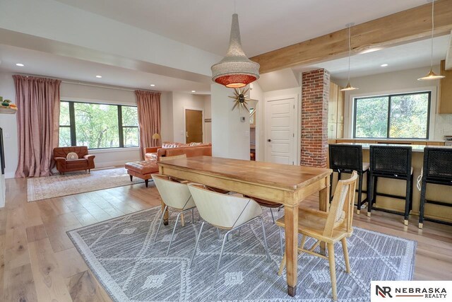 dining room featuring light hardwood / wood-style flooring and beam ceiling