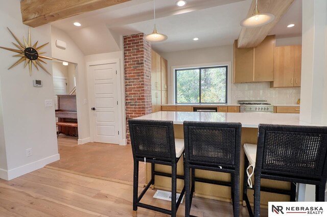 kitchen with kitchen peninsula, light brown cabinets, stove, and a kitchen breakfast bar