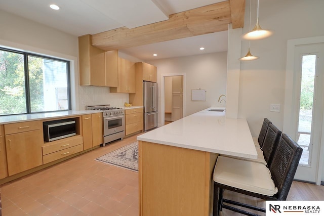 kitchen with kitchen peninsula, light brown cabinetry, decorative light fixtures, sink, and stainless steel appliances