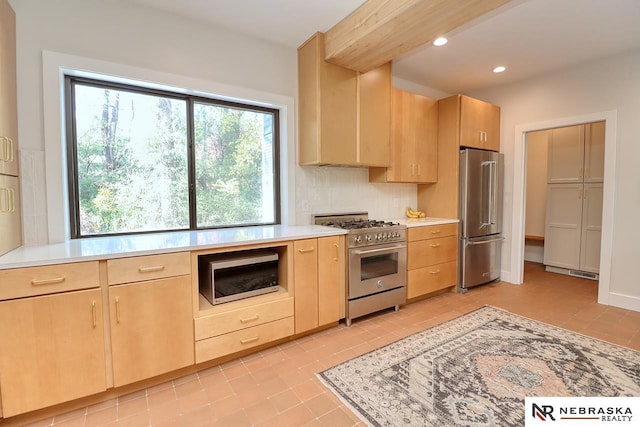 kitchen featuring high end appliances, light brown cabinetry, light tile patterned floors, and decorative backsplash