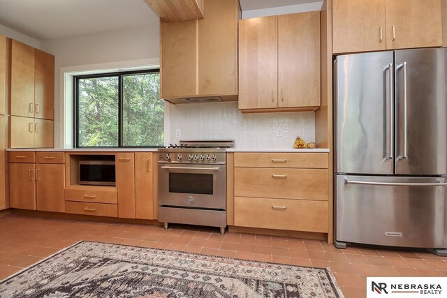 kitchen with extractor fan, light tile patterned floors, decorative backsplash, high quality appliances, and light brown cabinets