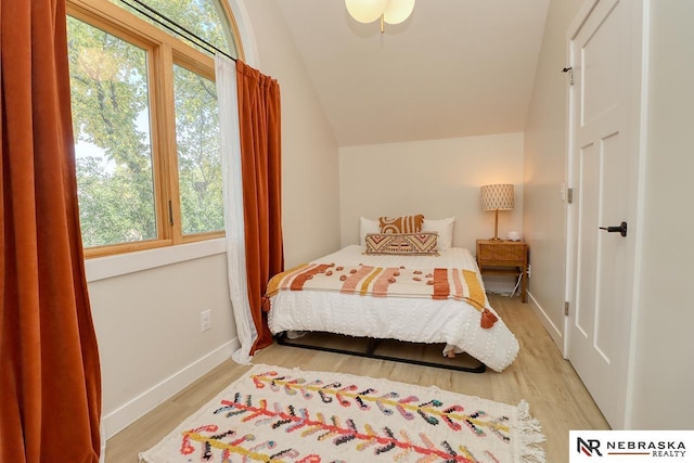 bedroom with light wood-type flooring and vaulted ceiling