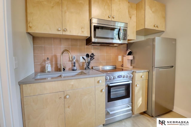 kitchen with sink, light brown cabinetry, appliances with stainless steel finishes, and decorative backsplash