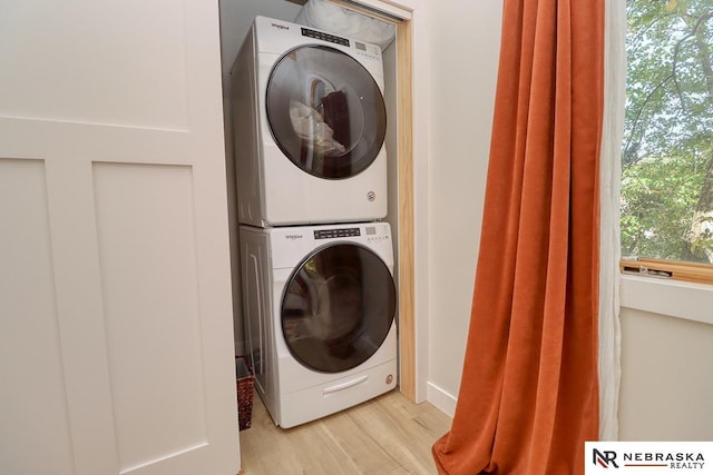 laundry area featuring stacked washer / drying machine and light hardwood / wood-style flooring