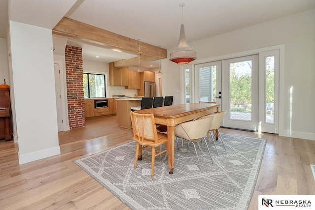 dining room featuring light wood-type flooring, beam ceiling, and french doors