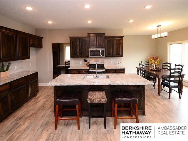 kitchen with light stone counters, sink, appliances with stainless steel finishes, and an island with sink