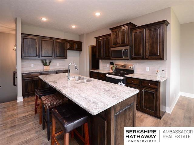 kitchen featuring stainless steel appliances, light hardwood / wood-style floors, sink, backsplash, and a center island with sink