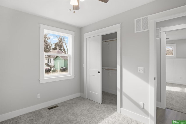 unfurnished bedroom featuring multiple windows, light colored carpet, a closet, and ceiling fan