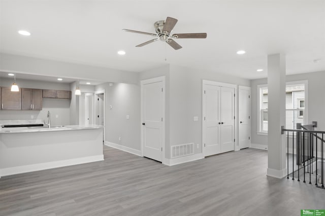 unfurnished living room featuring sink, hardwood / wood-style flooring, and ceiling fan