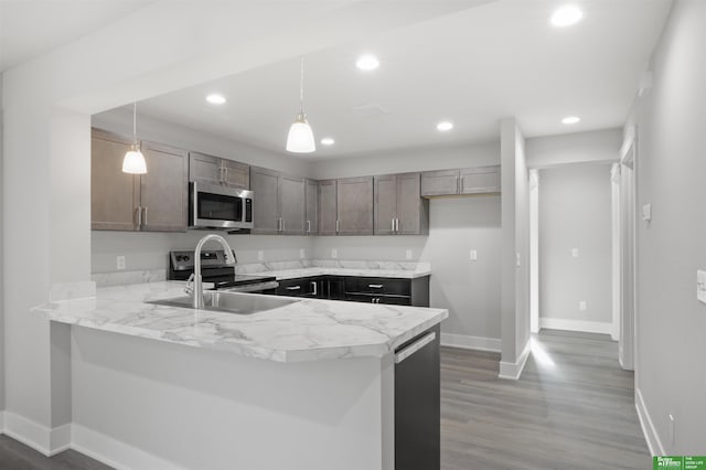 kitchen with kitchen peninsula, pendant lighting, sink, and stainless steel appliances