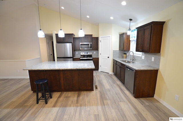 kitchen with sink, stainless steel appliances, a kitchen island, and decorative backsplash