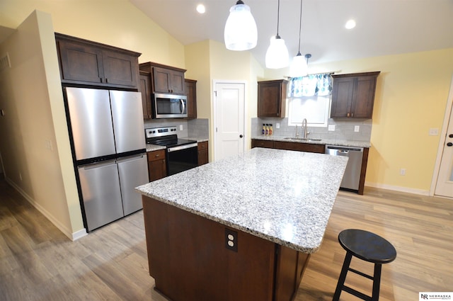 kitchen featuring decorative backsplash, sink, a kitchen island, dark brown cabinets, and stainless steel appliances