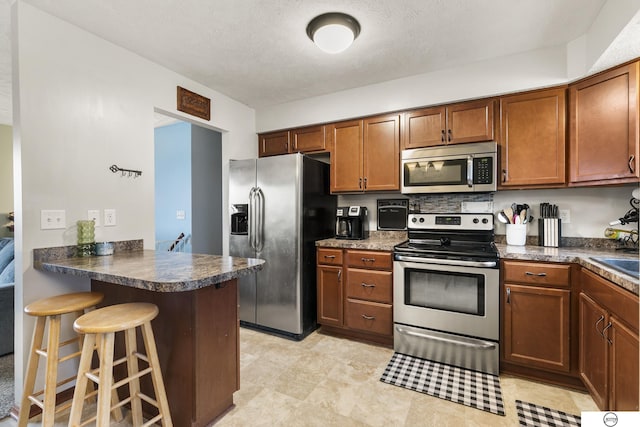 kitchen with sink, kitchen peninsula, stainless steel appliances, and a breakfast bar area