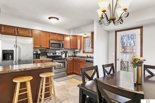 kitchen featuring decorative light fixtures, stainless steel appliances, an inviting chandelier, sink, and a breakfast bar area