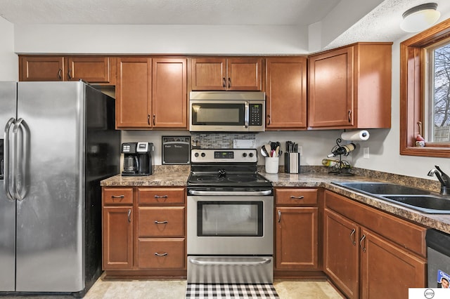 kitchen with sink, a textured ceiling, and stainless steel appliances