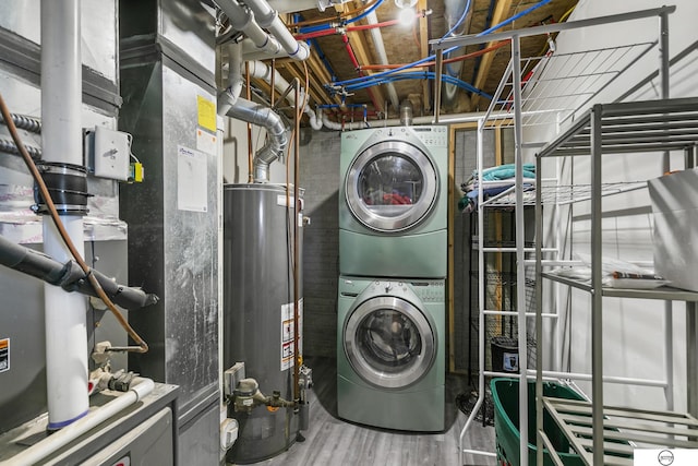 clothes washing area featuring hardwood / wood-style floors, gas water heater, heating unit, and stacked washer and dryer