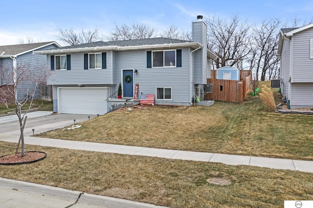 split foyer home featuring central air condition unit, a garage, and a front lawn