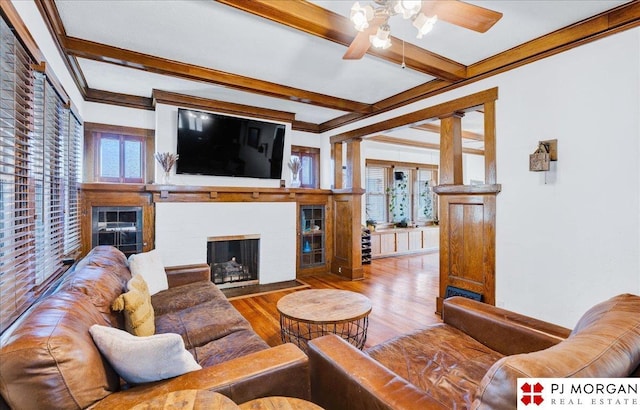 living room featuring ceiling fan, beam ceiling, crown molding, and wood-type flooring