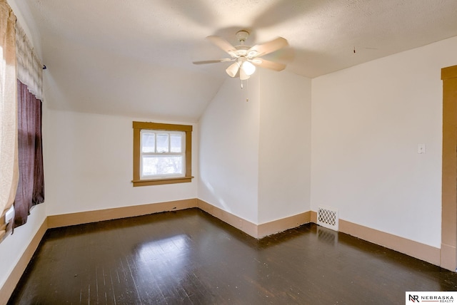 unfurnished room with ceiling fan, a textured ceiling, dark hardwood / wood-style floors, and vaulted ceiling