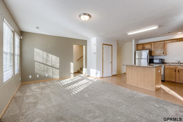 kitchen featuring sink, light colored carpet, a center island, and appliances with stainless steel finishes