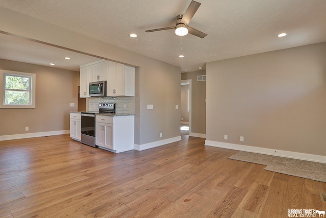 kitchen featuring white cabinetry, appliances with stainless steel finishes, light stone countertops, light hardwood / wood-style floors, and decorative backsplash