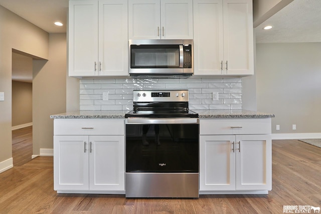 kitchen featuring light stone counters, tasteful backsplash, stainless steel appliances, and white cabinets