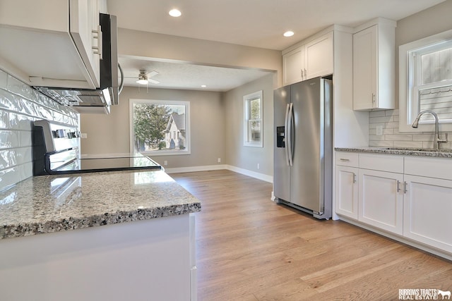 kitchen with tasteful backsplash, sink, white cabinets, stainless steel fridge, and stove