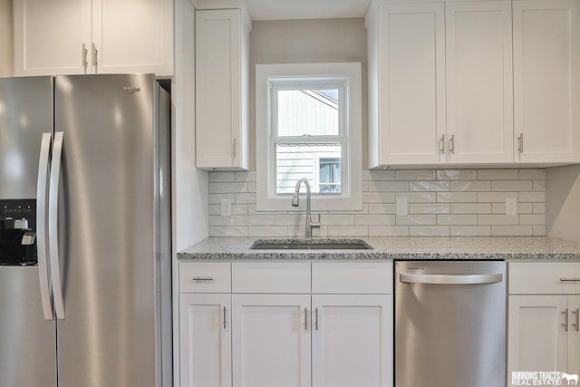 kitchen with sink, white cabinetry, tasteful backsplash, stainless steel appliances, and light stone countertops