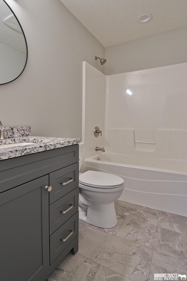 full bathroom featuring vanity, a textured ceiling,  shower combination, and toilet