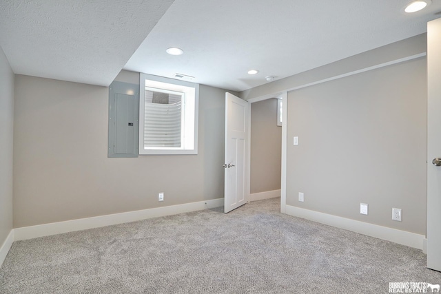 basement featuring light carpet, electric panel, and a textured ceiling