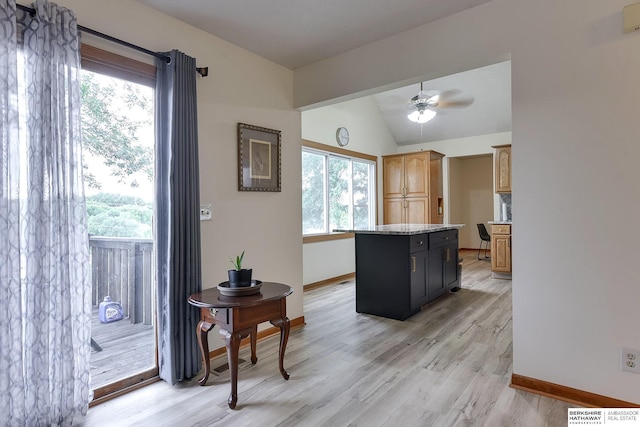 kitchen with light hardwood / wood-style flooring, vaulted ceiling, a kitchen island, and a wealth of natural light