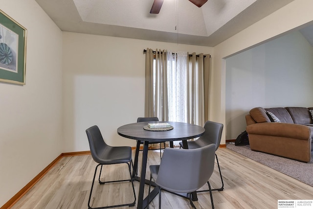 dining area featuring ceiling fan, a tray ceiling, and light hardwood / wood-style floors