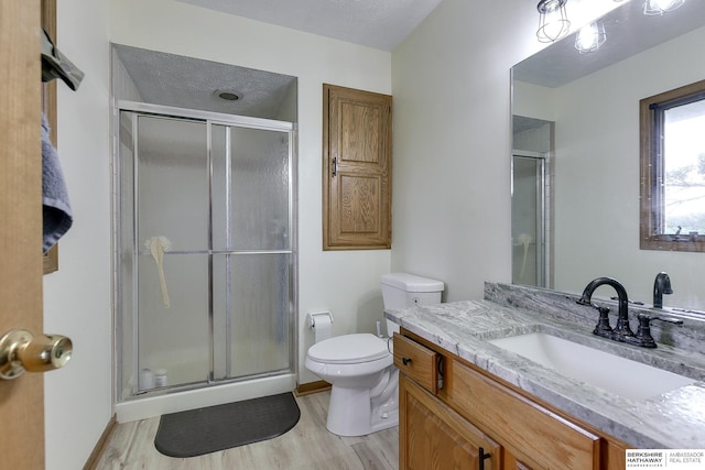 bathroom featuring vanity, wood-type flooring, a textured ceiling, toilet, and walk in shower