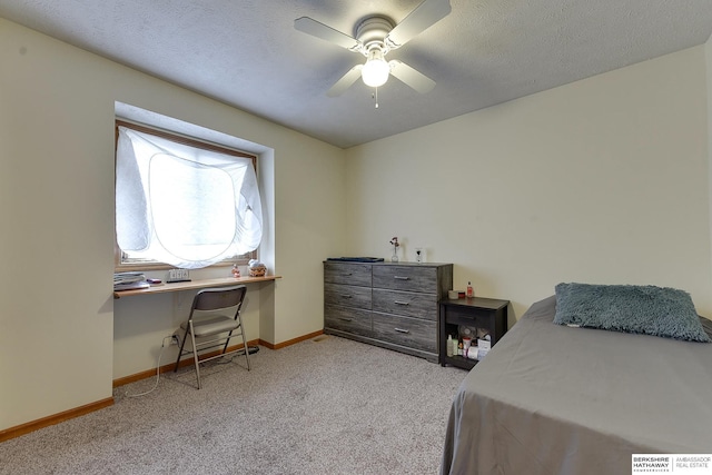 bedroom featuring ceiling fan, light colored carpet, and a textured ceiling