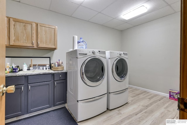 laundry room with light hardwood / wood-style floors, sink, washing machine and dryer, and cabinets