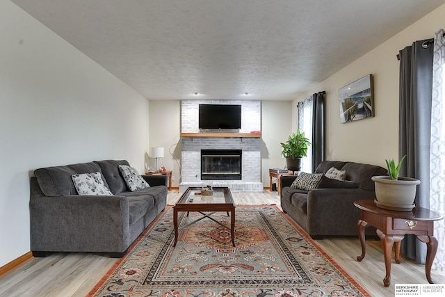 living room with a textured ceiling, light hardwood / wood-style floors, and a fireplace