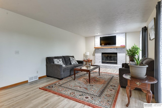 living room with a fireplace, light hardwood / wood-style floors, and a textured ceiling