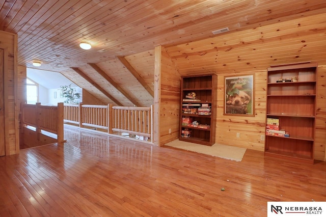 additional living space with lofted ceiling, hardwood / wood-style floors, wooden ceiling, and wood walls