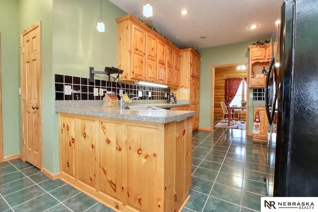 kitchen featuring sink, black refrigerator, decorative backsplash, decorative light fixtures, and kitchen peninsula