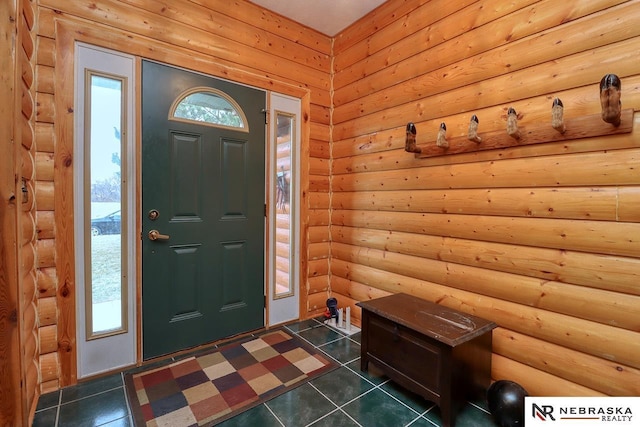 entryway with log walls and dark tile patterned floors